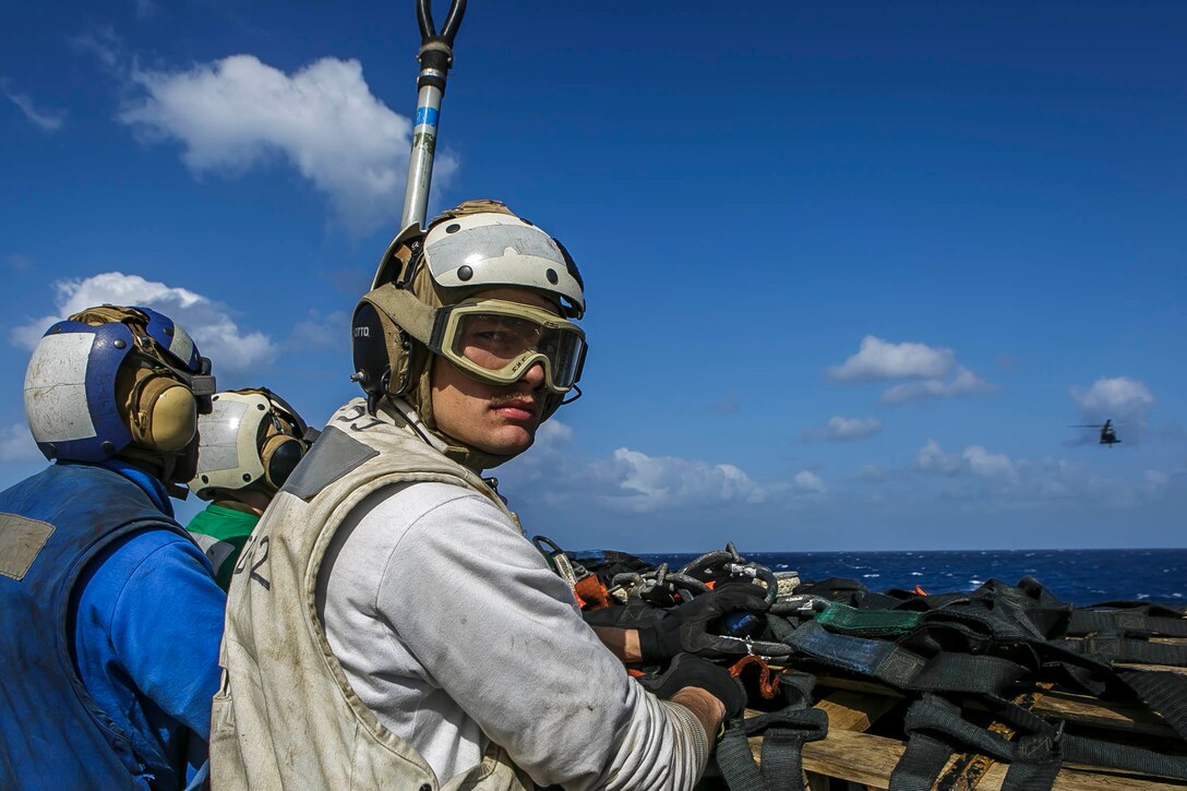 Marines and Sailors assigned to the Harpers Ferry-class dock landing ship USS Oak Hill (LSD 51) prepare to hook items for transport onto an MH-60S Seahawk helicopter attached to Helicopter Sea Combat Squadron (HSC) 28, during a replenishment-at-sea in the Aegean Sea March 24, 2018. Oak Hill, home-ported in Virginia Beach, Virginia, and the 26th MEU are conducting naval operations in the U.S. 6th Fleet area of operations. (U.S. Marine Corps photo by Staff Sgt. Dengrier M. Baez/Released)