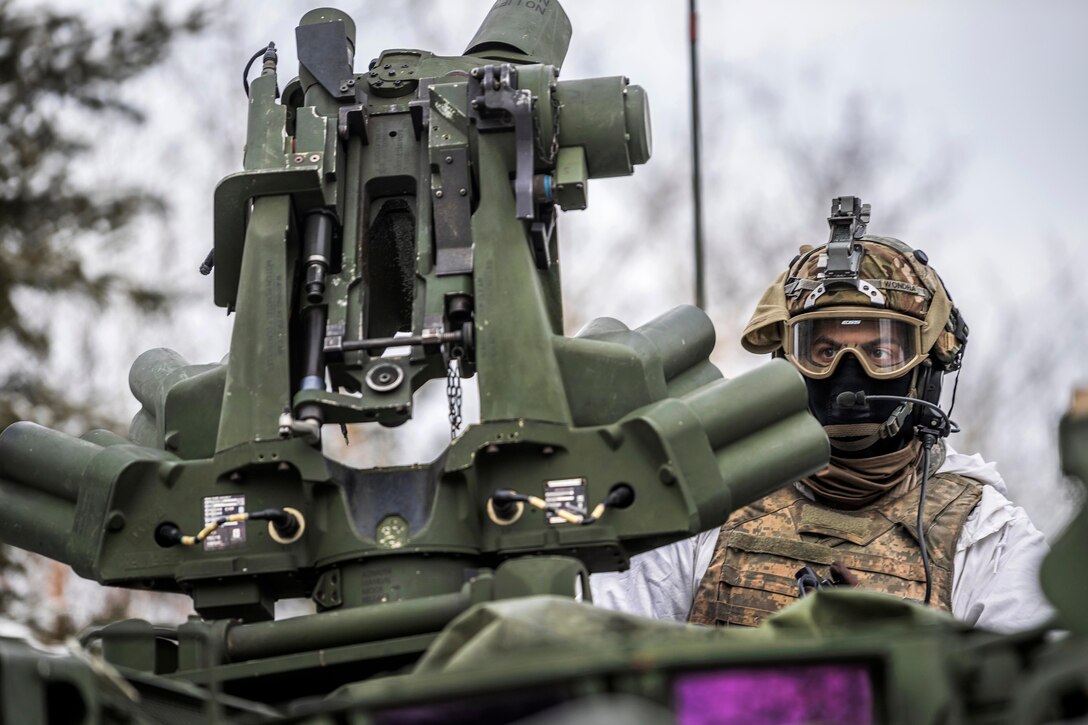 A soldiers scans the sector from the turret of a Stryker vehicle.