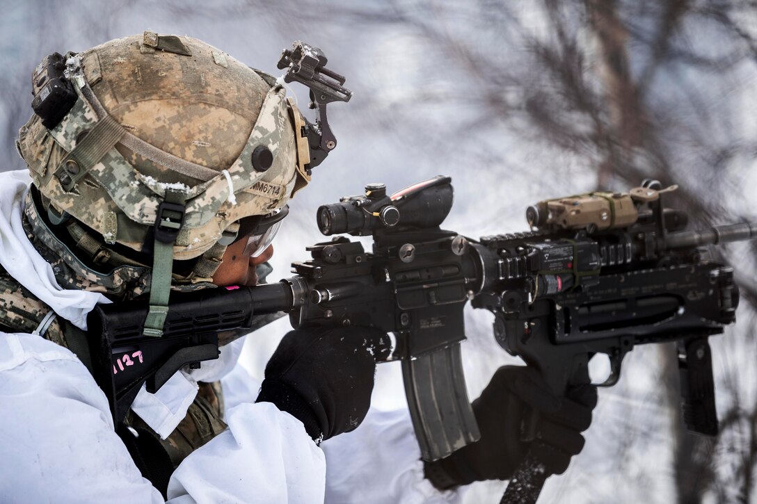 A soldiers aims his weapon at a target before firing.