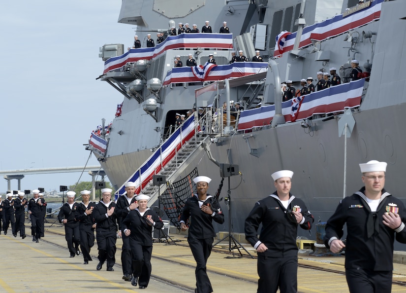 The USS Ralph Johnson’s (DDG-114) crew runs to man the ship during the commissioning ceremony March 24, 2018, at the Port of Charleston, S.C.