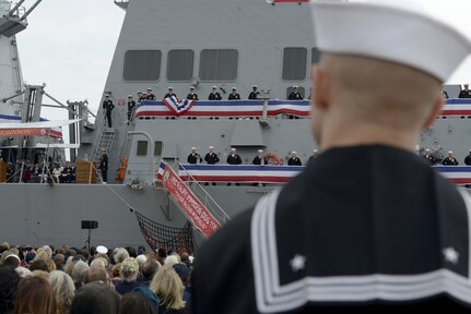 Crew members assemble on deck of the USS Ralph Johnson (DDG-114) during the commissioning ceremony March 24, 2018 in the Port of Charleston, S.C.