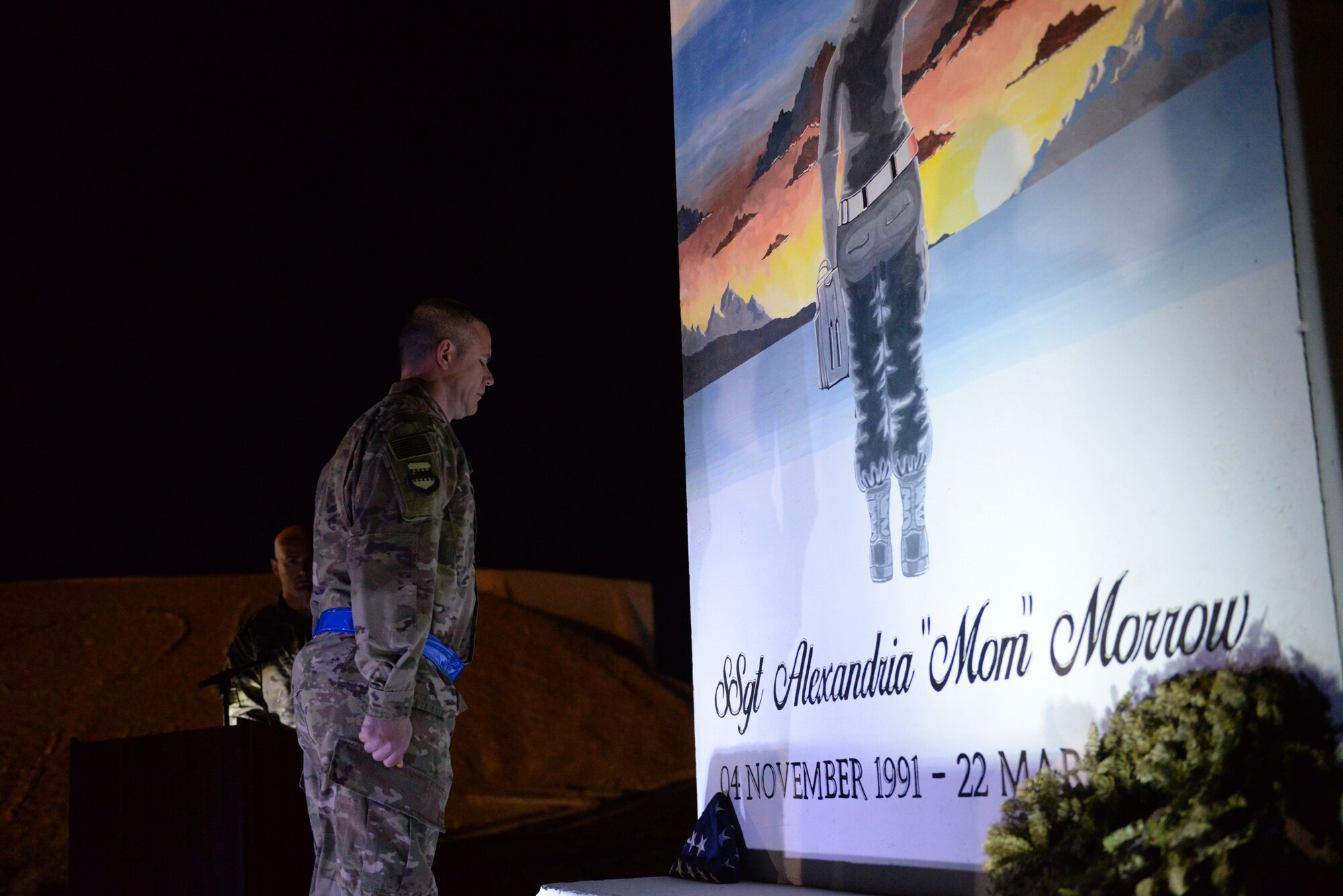 Chief Master Sgt. Dennis Fuselier 332nd Expeditionary Maintenance Group wing weapons manager, stands at attention before saluting the American flag and T-wall of Staff Sgt. Alexandria Morrow during her remembrance ceremony March 22, 2018, at an undisclosed location in Southwest Asia. Maintenance personnel gathered at her T-wall to observe a moment of silence and perform a flag folding ceremony before concluding with Taps.  She passed away during a bomb loading accident March 22, 2017. (U.S. Air Force photo by Senior Master Sgt. Cohen A. Young)
