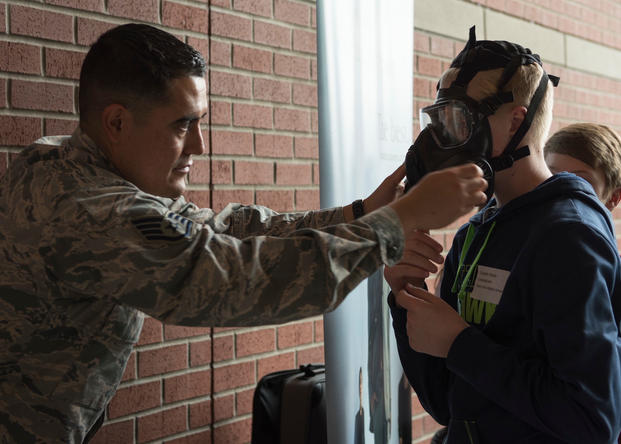 Staff Sgt. Gerardo Salas, 92nd Medical Group Bioenvironmental engineer, helps Dustin Ylitalo, Deer Park Middle School student, with a M50 gas mask at an informational booth during the  Eastern Washington Regional Science and Engineering Fair at the Spokane Washington State University campus, Washington, March 15, 2018. Members of Team Fairchild attended the fair to provide visiting students with information about the science, technology, engineering and math related fields that the U.S. Air Force offers. (U.S. Air Force photo/Senior Airman Ryan Lackey)