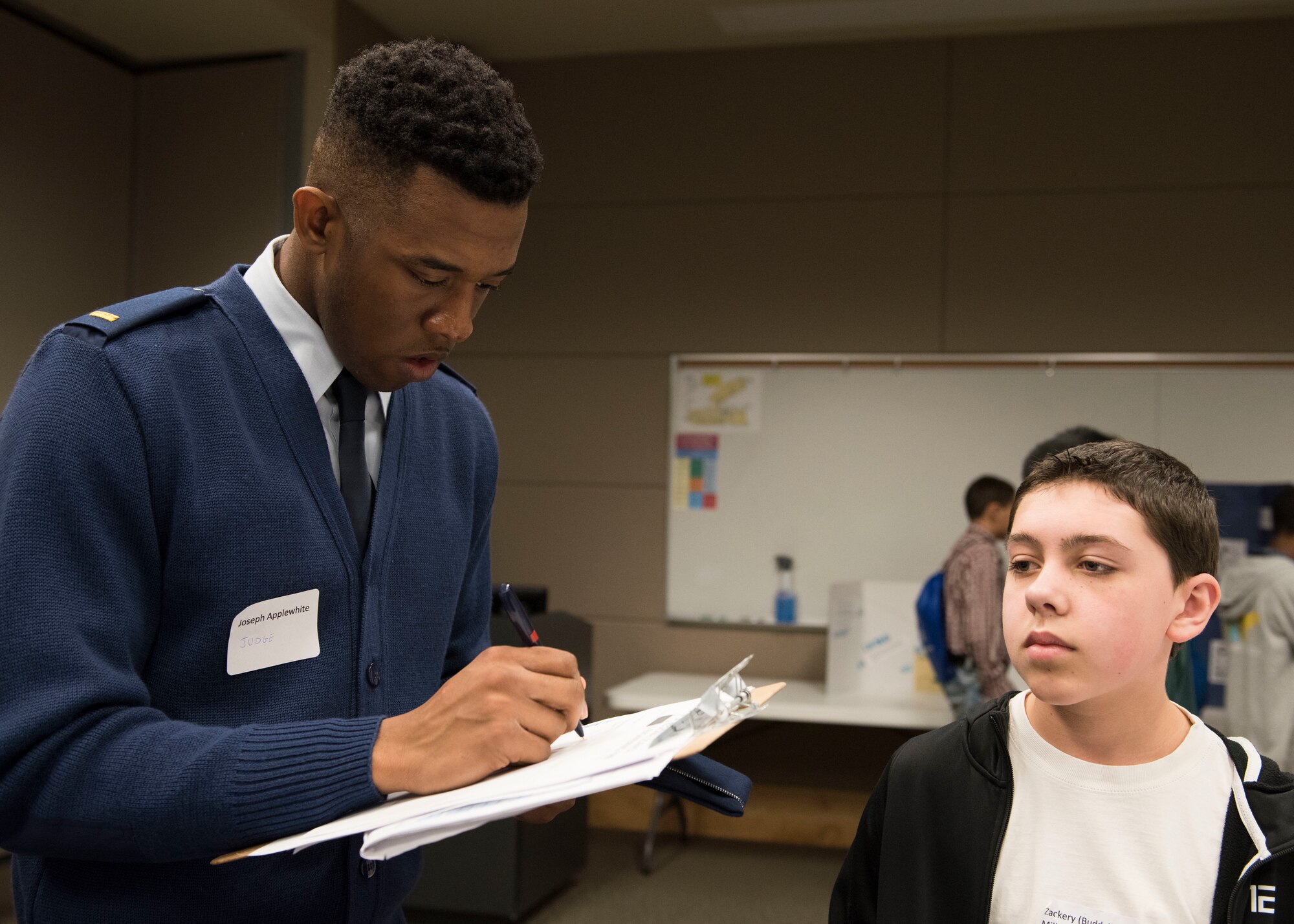 2nd Lt. Joseph Applewhite, 92nd Force Support Squadron officer promotion manager, scores the project of Zachery Miller, Deer Park Middle School student, during the Eastern Washington Regional Science and Engineering Fair at the Spokane Washington State University campus, Washington, March 15, 2018. Team Fairchild officers and Airmen were invited by WSU to help with the preliminary judging of the students projects. (U.S. Air Force photo/Senior Airman Ryan Lackey)