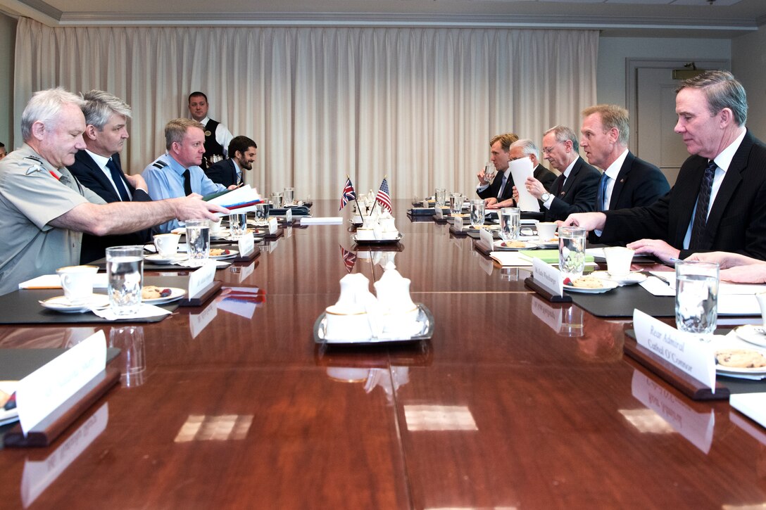 Defense leaders meet around a table at the Pentagon.