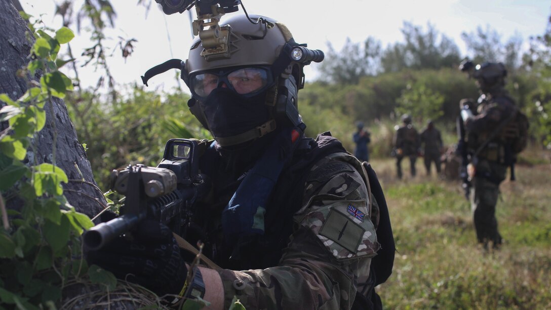 A British Royal Marine Commando holds security during a simulated raid in Guam March 22, 2018. U.S. Marines with Force Reconnaissance Company, 3rd Reconnaissance Battalion, 3rd Marine Division, III Marine Expeditionary Force; British Royal Marines with J Company, 42 Commando and Sailors with Explosive Ordinance Disposal Mobile Unit 5 conduct raids as part of regularly scheduled training. The units are conducting joint, combined training in order to develop shared standard-of-procedures in a visit, board, search and seizure environment so they can provide a more flexible and mission-ready capability to geographic combatant commanders in the Pacific.