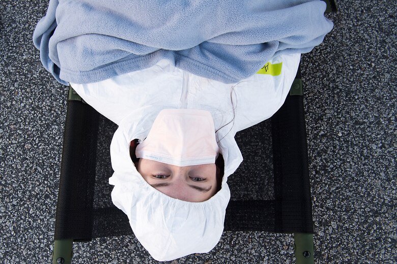 Airman Helena Owens, 628th Air Base Wing public affairs photojournalist, is prepped as a patient role-player during a transportable isolation system scenario at Joint Base Charleston, S.C., March 14, 2018.