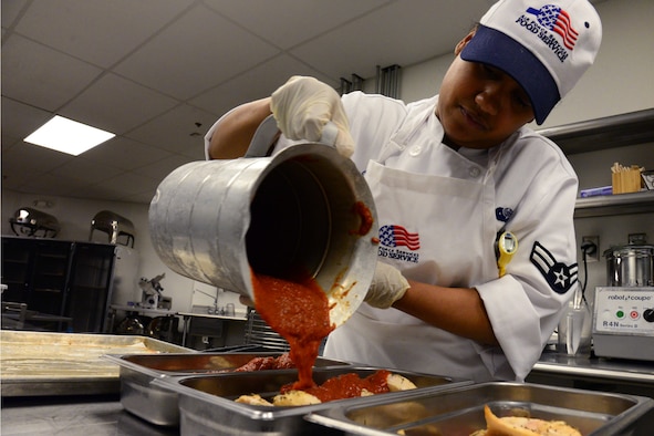 Airman 1st Class Elizabeth Bautista, 341st Force Support Squadron food services apprentice, pours tomato sauce onto chicken Mar. 7, 2018, at Malmstrom Air Force Base, Mont.