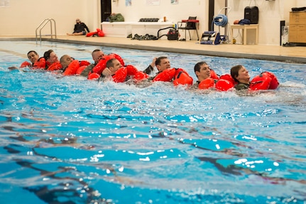 Survival, evasion, resistance and escape specialists with the 3rd Operations Support Squadron conduct a water-survival refresher course for pilots and aircrew at the Elmendorf Fitness Center on Joint Base Elmendorf-Richardson, Alaska, March 20, 2018. The course consisted of safely escaping from under a parachute, using recovery tools, simulating a parachute drag, and various other techniques.
