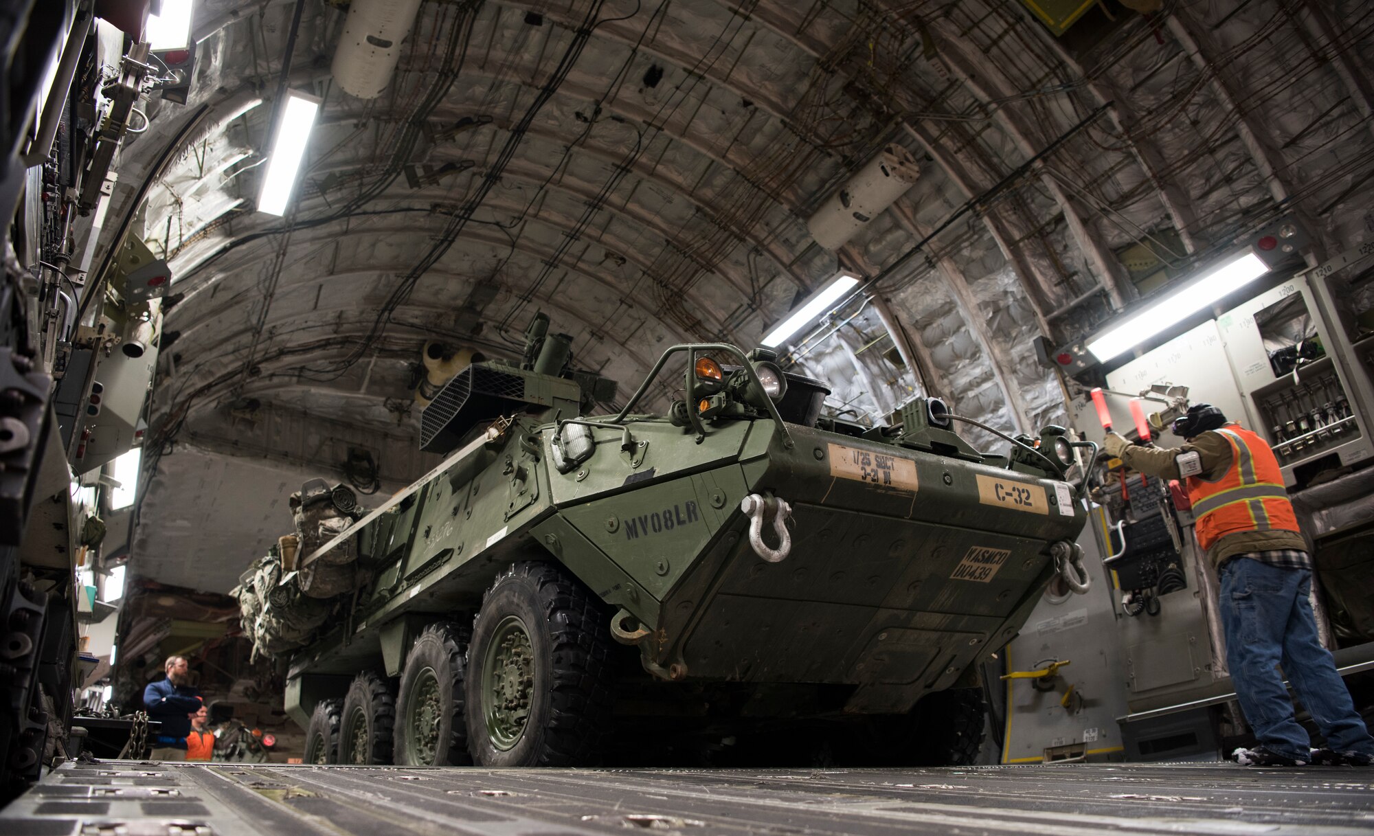 Danny Batchelor, 445th Expeditionary Aerial Port Squadron nightshift foreman, directs a U.S. Army Interim Armored Vehicle Stryker onto a C-17 Globemaster III at Elmendorf Air Force Base, Alaska, March 13, 2018. Airmen assigned to the 62nd Airlift Wing participated in the exercise to practice cold-weather operations. (U.S. Air Force photo by Senior Airman Tryphena Mayhugh)