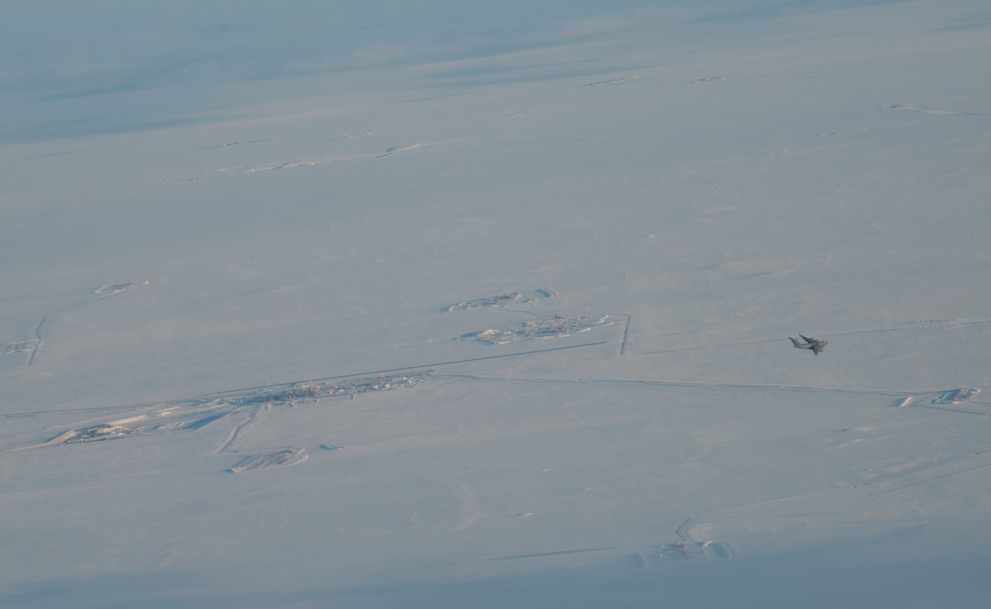 A C-17 Globemaster III flies over Deadhorse, Alaska, during Exercise Artic Pegasus March 13, 2018. Deadhorse is one of the farthest northern points in Alaska and presented an opportunity for the Air Force and Army to practice operating in cold weather together during the exercise. (U.S. Air Force photo by Senior Airman Tryphena Mayhugh)