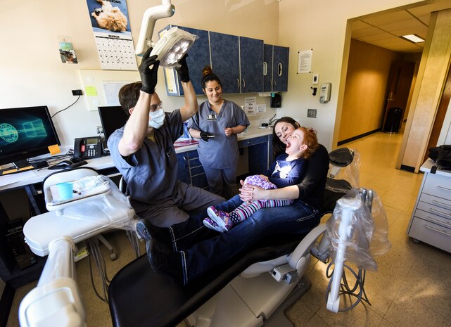 Capt. Matthew Burns, far left, 628th Aeromedical Squadron general dentist, prepares to examine a patient during the Give Kids A Smile event at Joint Base Charleston, S.C., March 23, 2018.