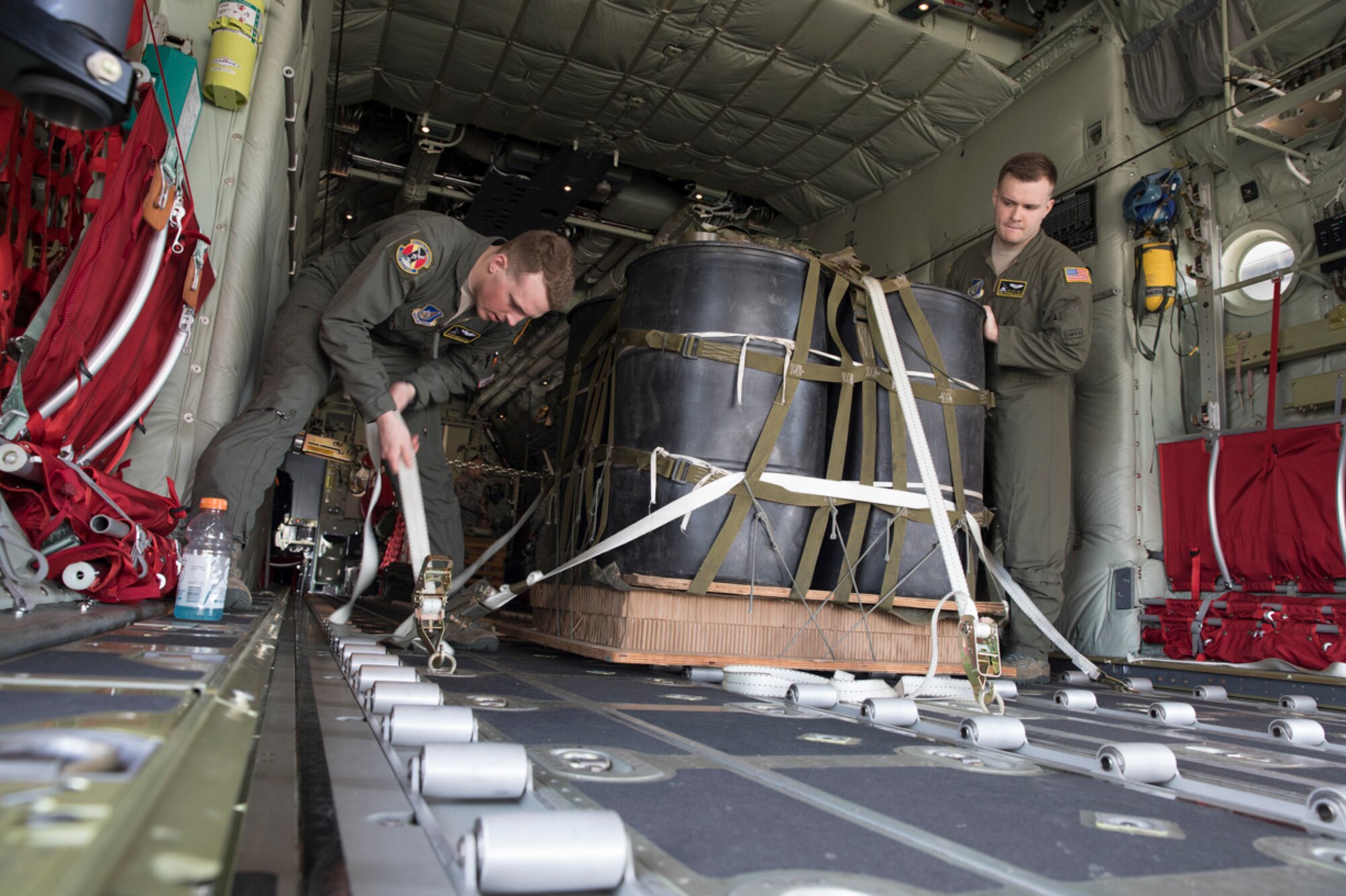 Airman 1st Class Matthew Pfeffer and Senior Airman Stephen Clark, both 36th Airlift Squadron C-130J loadmasters, secure a Container Delivery System (CDS) bundle onto a C-130J Super Hercules