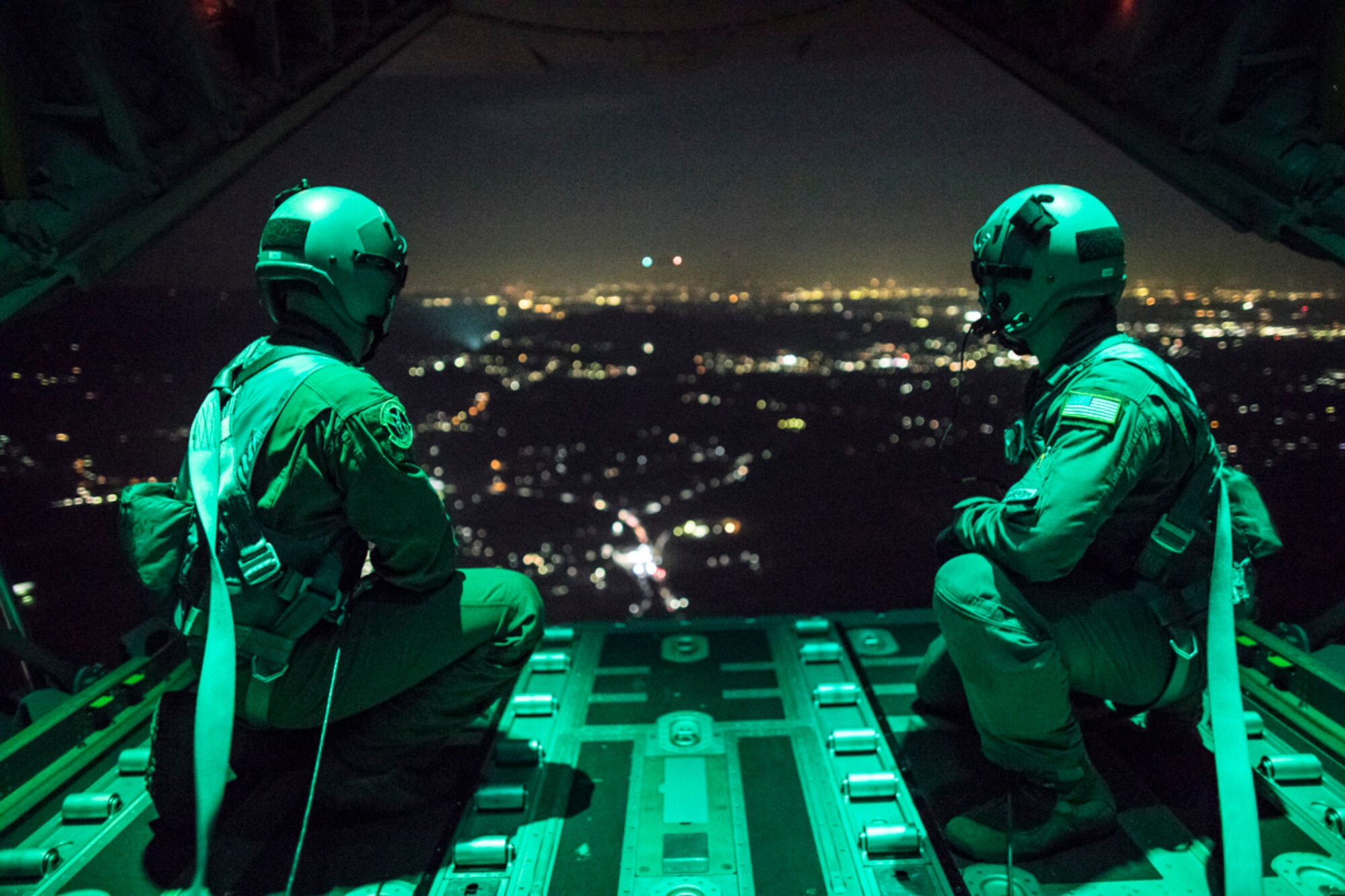 Senior Airman Stephen Clark and Airman 1st Class Matthew Pfeffer, 36th Airlift Squadron C-130J loadmasters, sit on the open ramp of a C-130J Super Hercules flying near Yokota Air Base