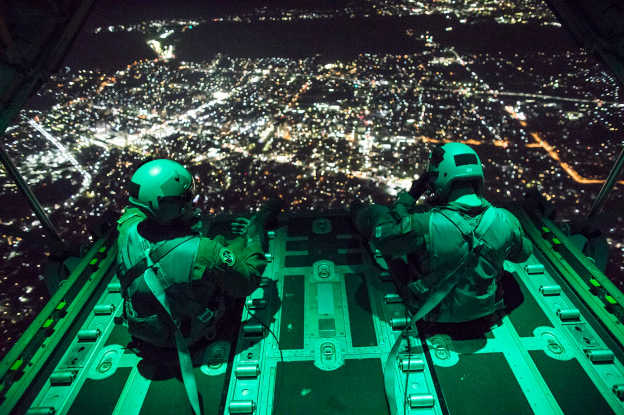 Senior Airman Stephen Clark and Airman 1st Class Matthew Pfeffer, 36th Airlift Squadron C-130J loadmasters, sit on the open ramp of a C-130J Super Hercules flying near Yokota Air Base