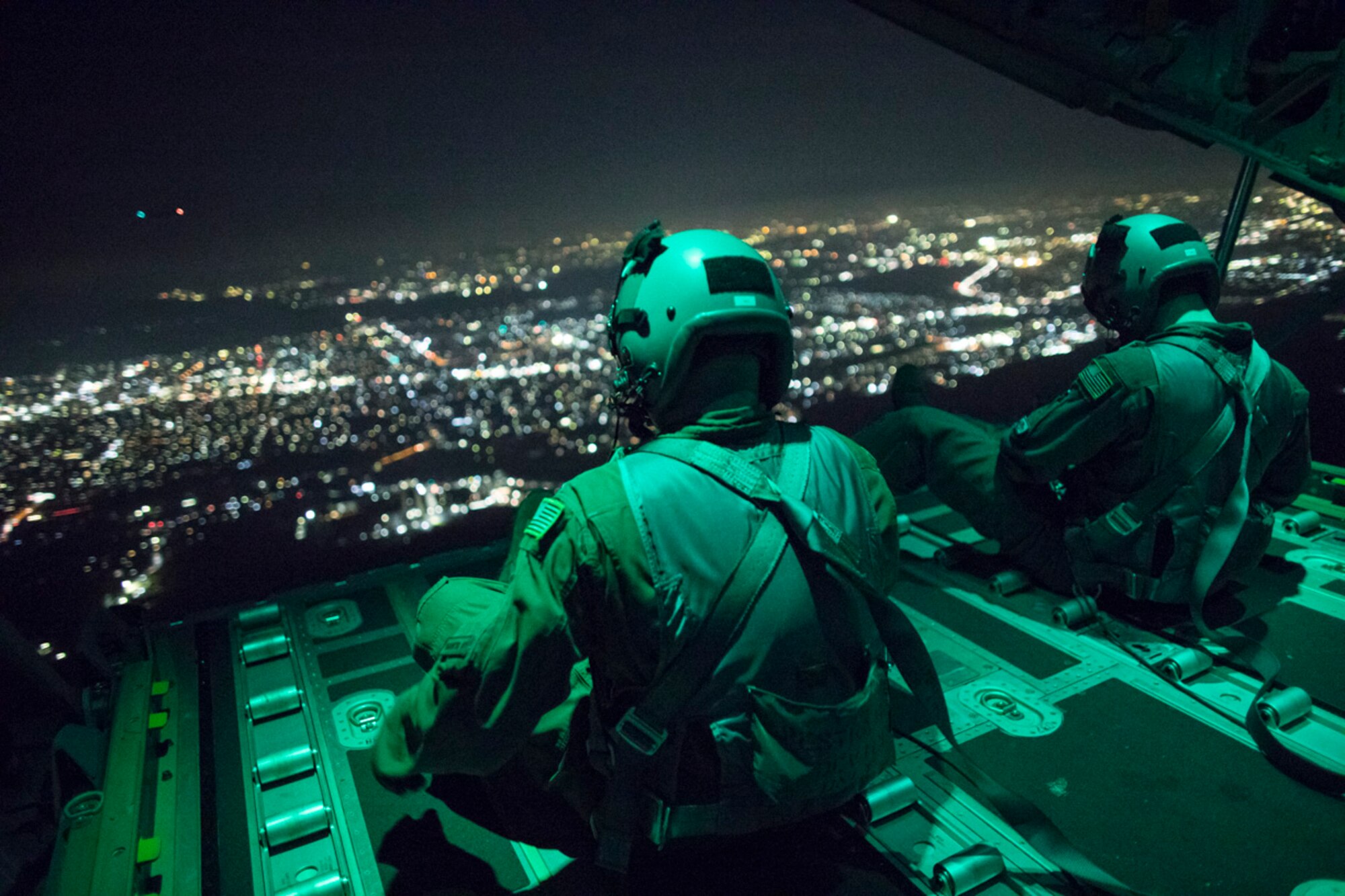 Senior Airman Stephen Clark and Airman 1st Class Matthew Pfeffer, 36th Airlift Squadron C-130J loadmasters, sit on the open ramp of a C-130J Super Hercules flying near Yokota Air Base, Japan