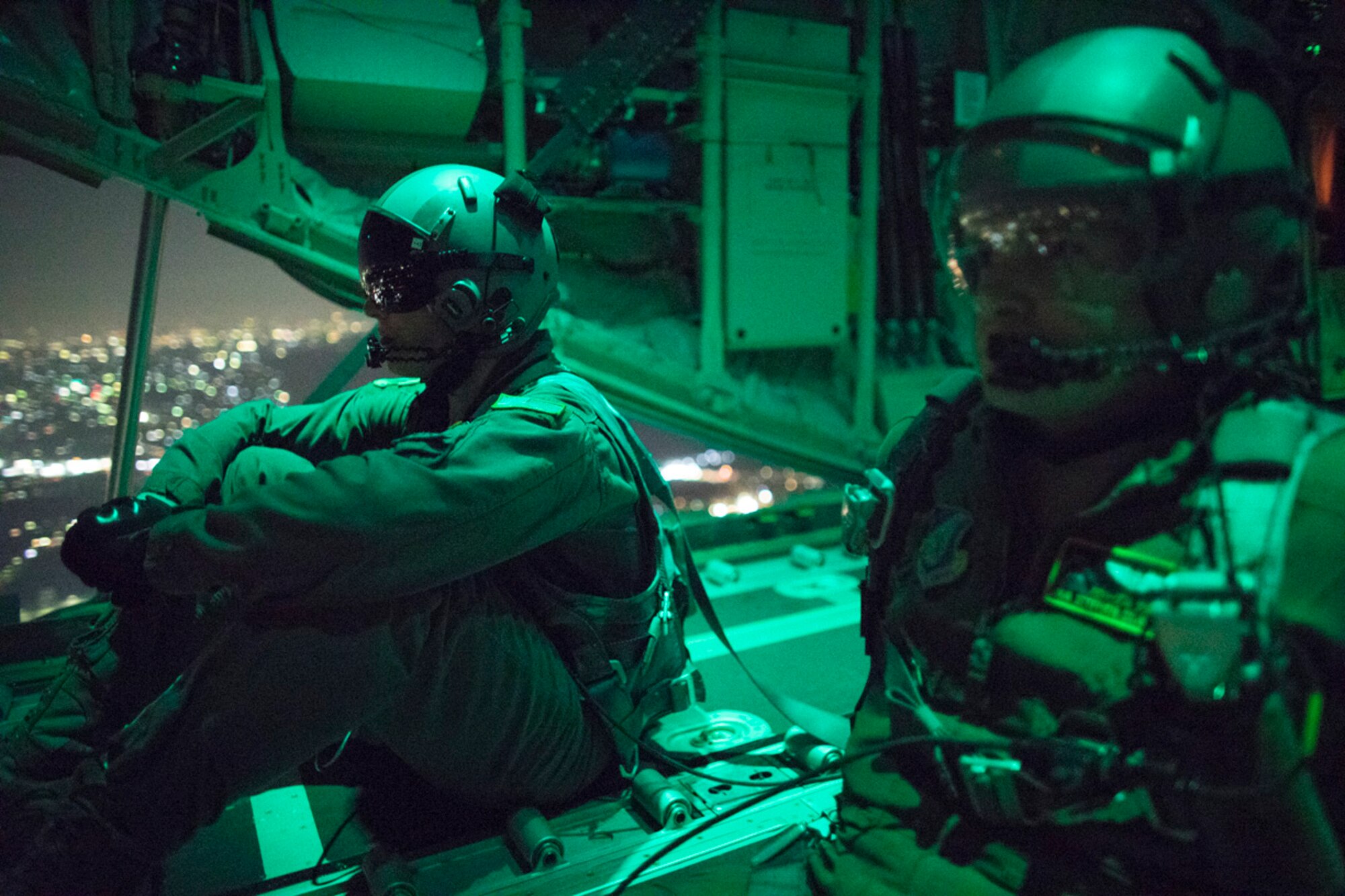 Senior Airman Stephen Clark and Airman 1st Class Matthew Pfeffer, 36th Airlift Squadron C-130J loadmasters, sit on the open ramp of a C-130J Super Hercules flying near Yokota Air Base