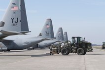 Airmen with the 374th Logistics Readiness Squadron and 36th Airlift Squadron load a Container Delivery System (CDS) bundle onto a C-130J Super Hercules