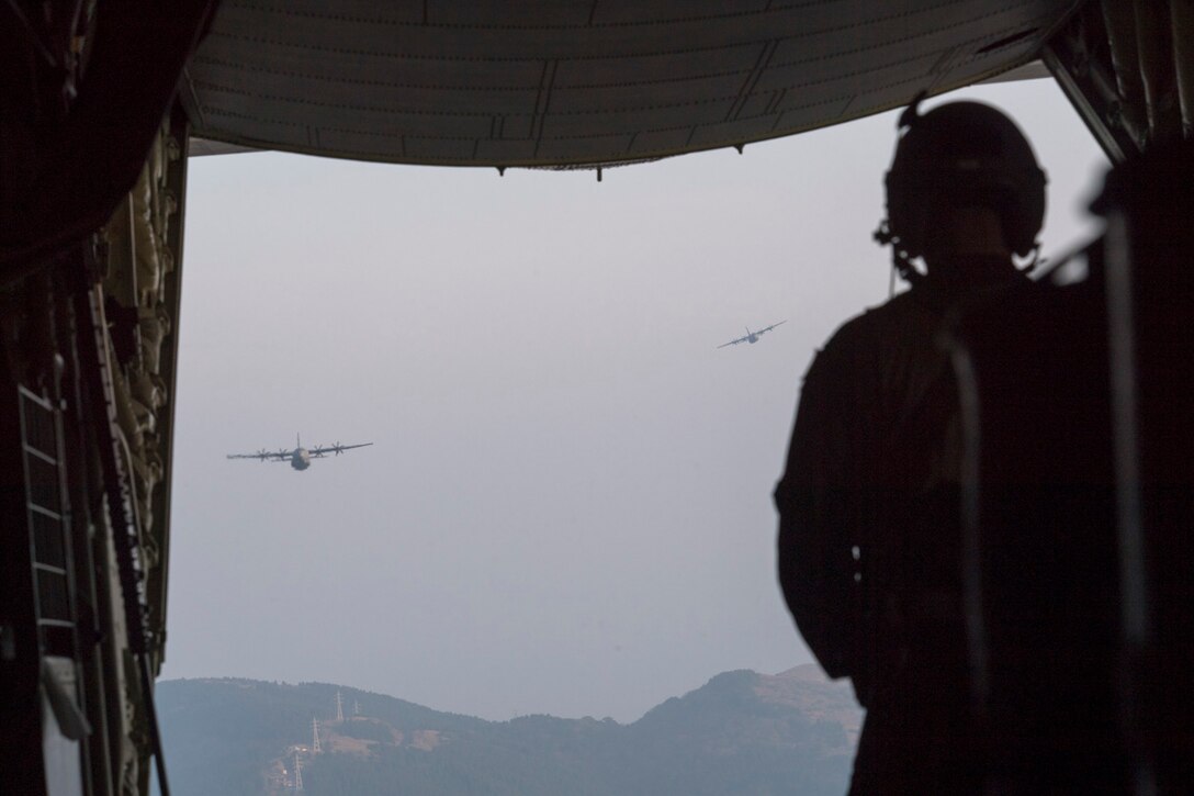 Airman 1st Class Matthew Pfeffer, 36th Airlift Squadron C-130J loadmaster, observes two Air Force C-130J Super Hercules over the Combined Arms Training Center Camp Fuji