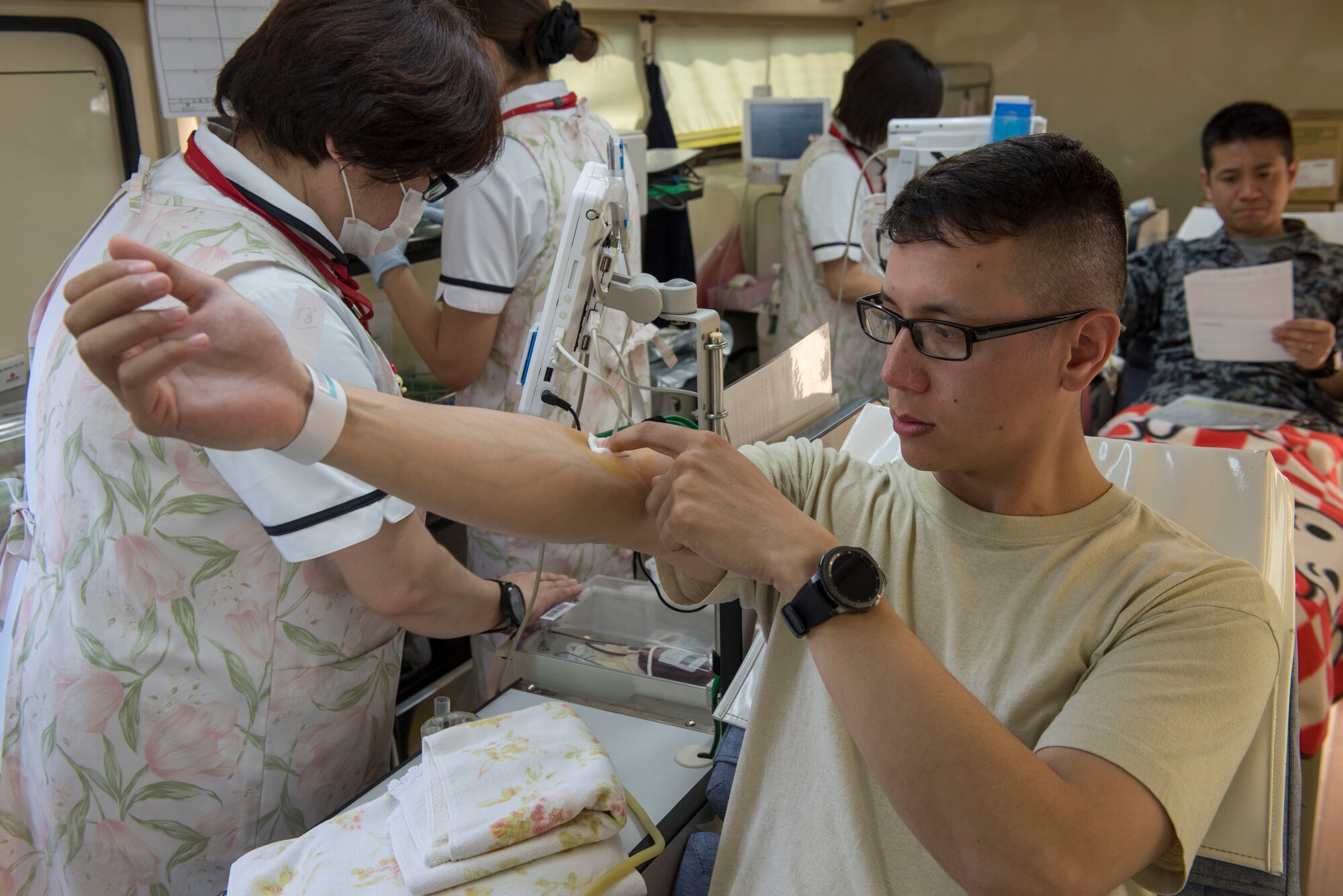 Staff Sgt. Michael Ober, 374th Operations Support Squadron NCO in charge of airfield management training, applies pressure to his arm after donating blood to the Japanese Red Cross Society at Yokota Air Base, Japan, March 28, 2018.