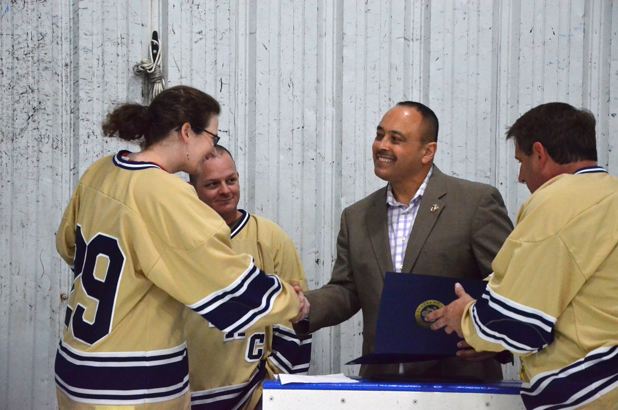Master Sgt. Rebecca Goodwin, a member of the Athletes for Teamwork and Charity hockey team at Patrick AFB, Fla., shakes the hand of Rob Medina, Director of Community Relations for Congressman Bill Posey (FL-15), where Media presented Certificates of Appreciation to the players for their fundraising efforts.  Also pictured are Tech. Sgt. Denton Kimber (second from left) and team captain Bill Hungate (right).  (U.S. Air Force photo by Susan A. Romano)