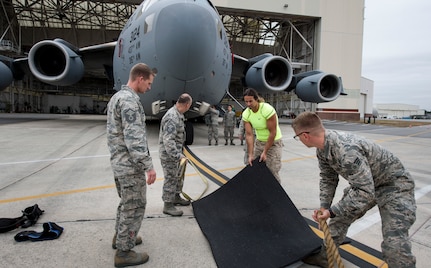 Airmen from the 437th Aircraft Maintenance Squadron and Mark Kirsch, strong man for “Man vs. Impossible,” setup for a practice session of pulling a C-17 Globemaster III from a hangar at Joint Base Charleston, S.C., March 27, 2018.
