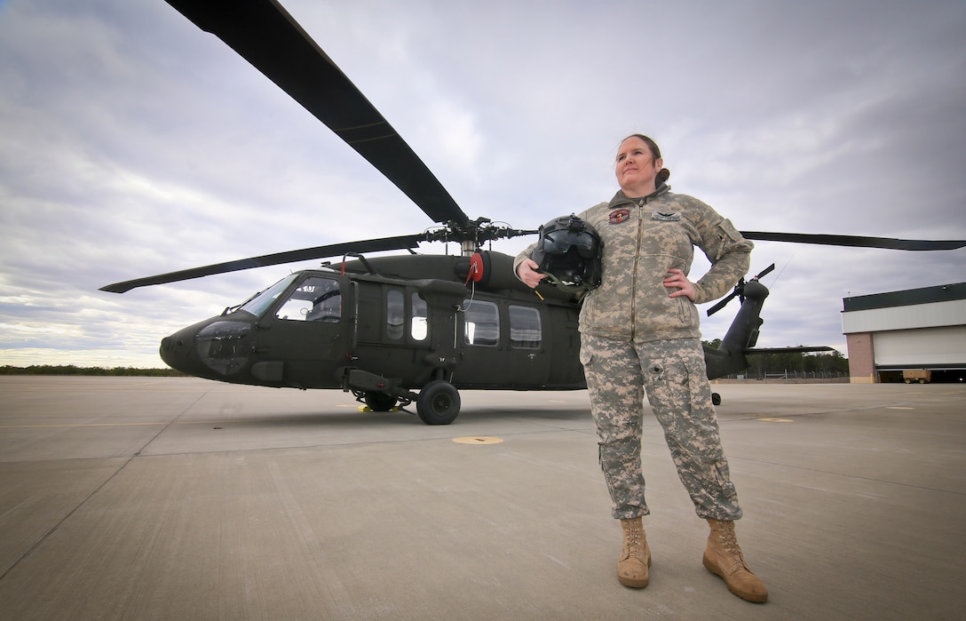 A soldier stands in front of a UH-60L Black Hawk helicopter.
