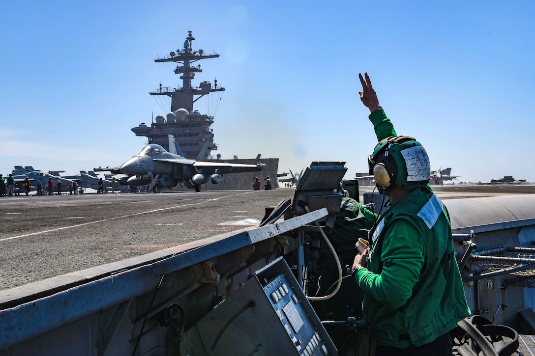 A sailor signals to an E/A-18G Growler.