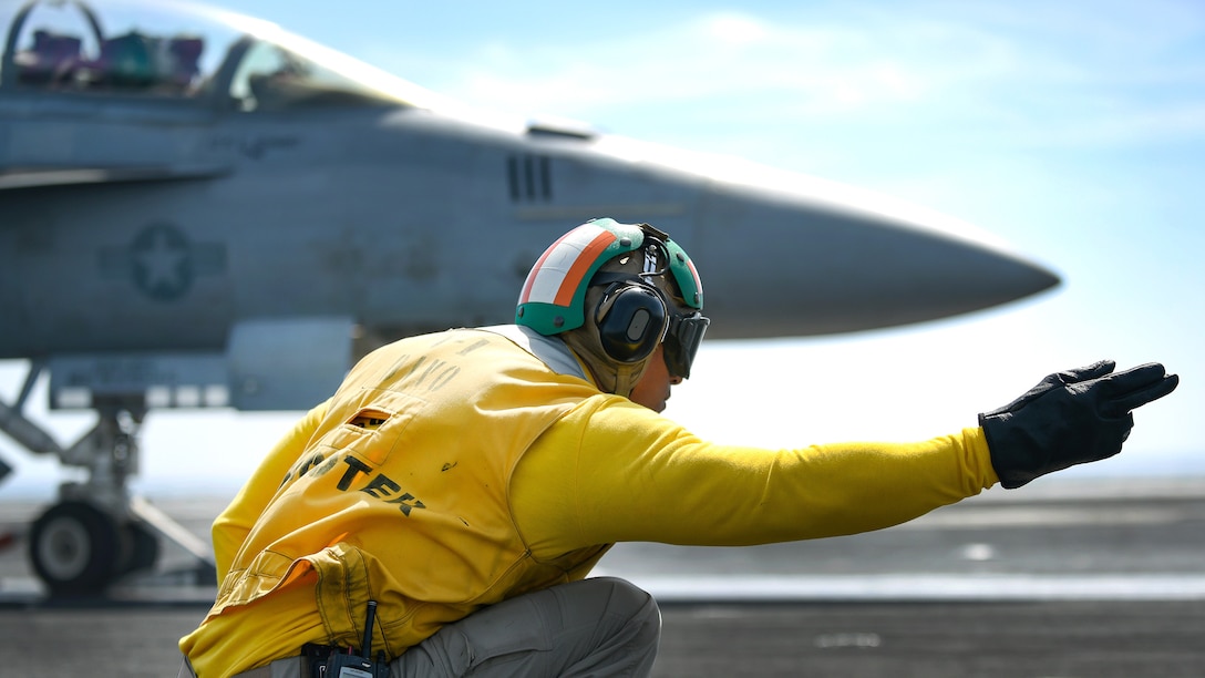 A sailor signals an F/A-18F Super Hornet.