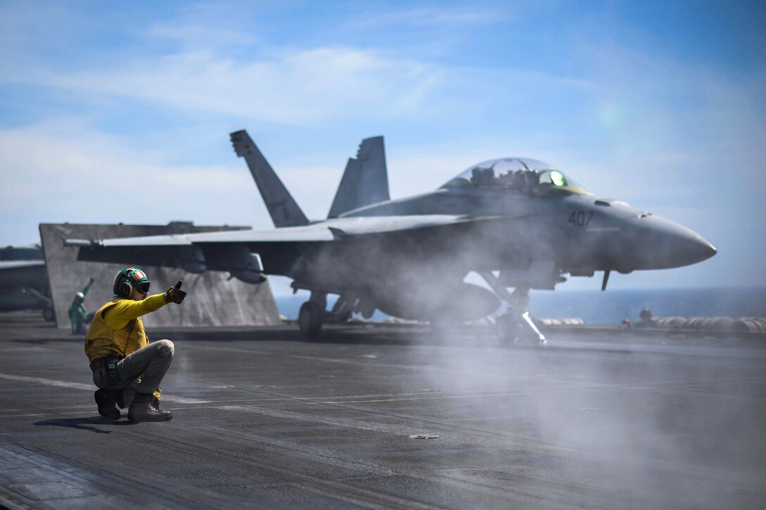 A sailor signals an F/A-18F Super Hornet.