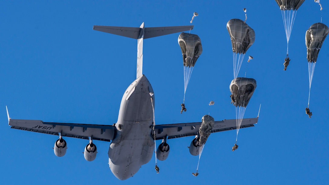Soldiers jump from an aircraft over a drop zone in Alaska during training.