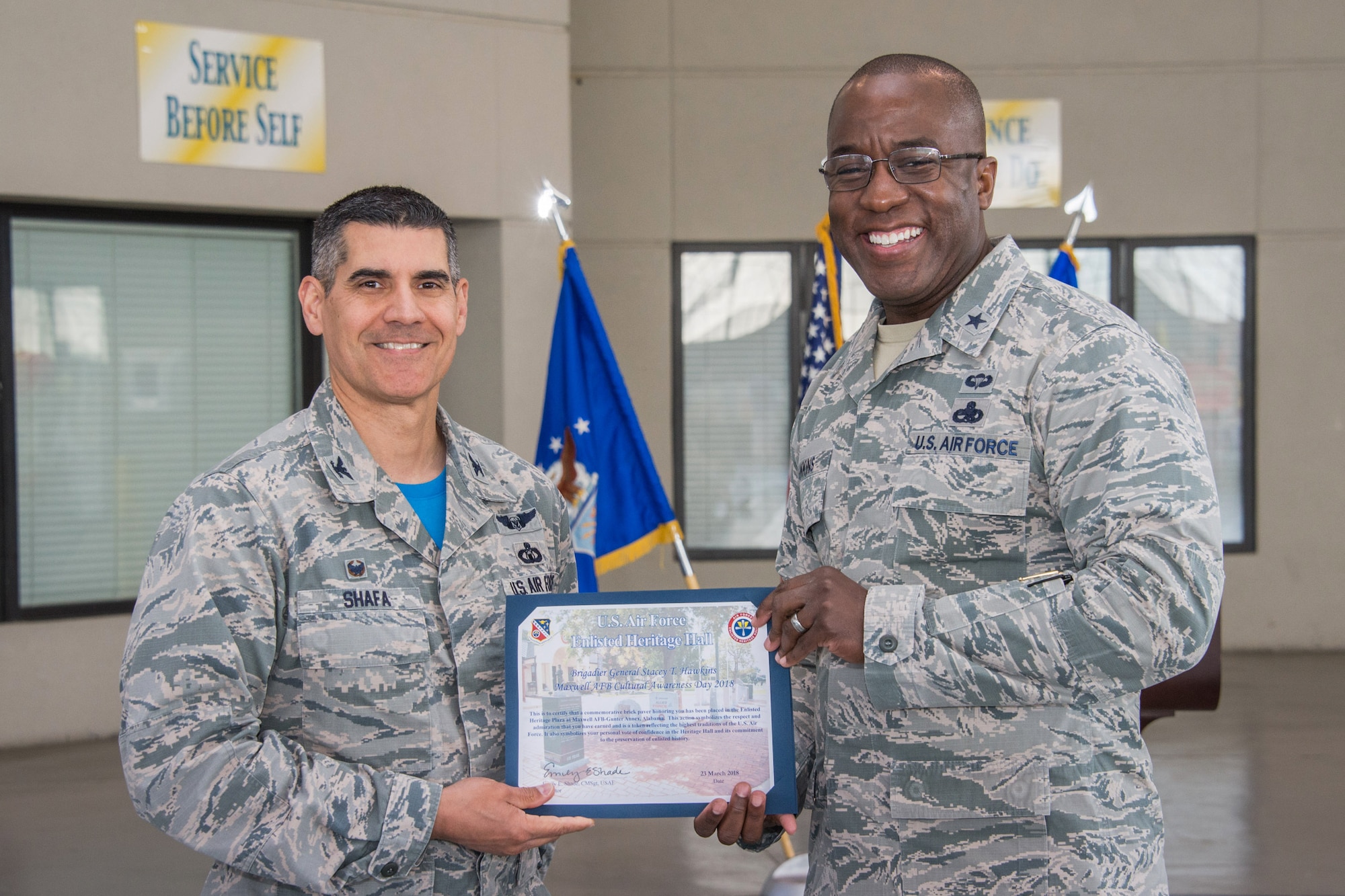 Col. Eric Shafa, 42nd Air Base Wing commander, presents Brig. Gen. Stacey T. Hawkins, Ogden Air Logistics Complex commander, Hill Air Force Base, Utah, with a certificate signifying the placement of a commemorative brick at the Air Force Enlisted Heritage Hall, Maxwell-Gunter Annex March 23, 2018. The AFEHH offers these bricks as a way to recognize a devoted career, to honor service or acknowledge the dedication of spouses, family members and others. (U.S. Air Force photo by William Birchfield)