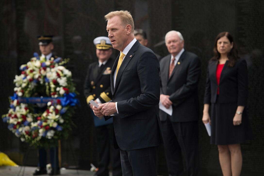 Deputy Defense Secretary Patrick M. Shanahan speaks while standing near a wreath in front of the Vietnam Veterans Memorial.