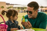 A Marine father holds two decorated eggs during a family day with his daughter.