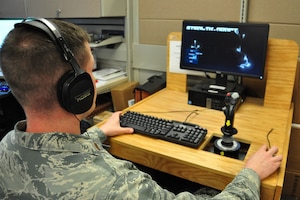 An air force officer sits in front of a computer monitor.