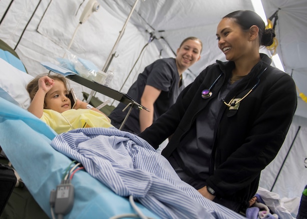 A Navy nurse laughs with a 4-year old Honduran girl while she waits for her hernia surgery.