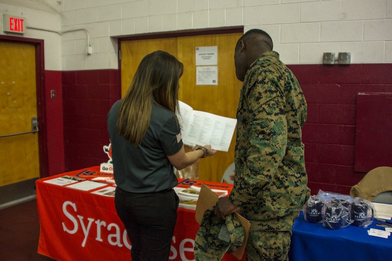 Jessica C. Calhoun, assistant director of student veteran and military admissions, Office of Admissions, Syracuse University, shows a Marine a catalog of courses that Syracuse offers during the Education & Career Fair aboard the Marine Corps Air Ground Combat Center, Twentynine Palms, Calif., March 21, 2018. The Education & Career Fair is a tool for Marines looking to further their education, develop new skills and explore new career fields. (U.S. Marine Corps photo by Lance Cpl. Rachel K. Porter)