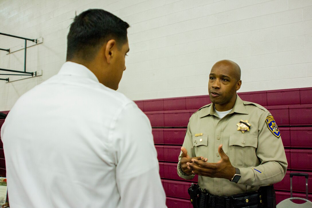 A Marine speaks to a California Highway Patrol officer about job opportunities during the Education & Career Fair aboard the Marine Corps Air Ground Combat Center, Twentynine Palms, Calif., March 21, 2018. The Education & Career Fair is a tool for Marines looking to further their education, develop new skills and explore new career fields. (U.S. Marine Corps photo by Lance Cpl. Rachel K. Porter)