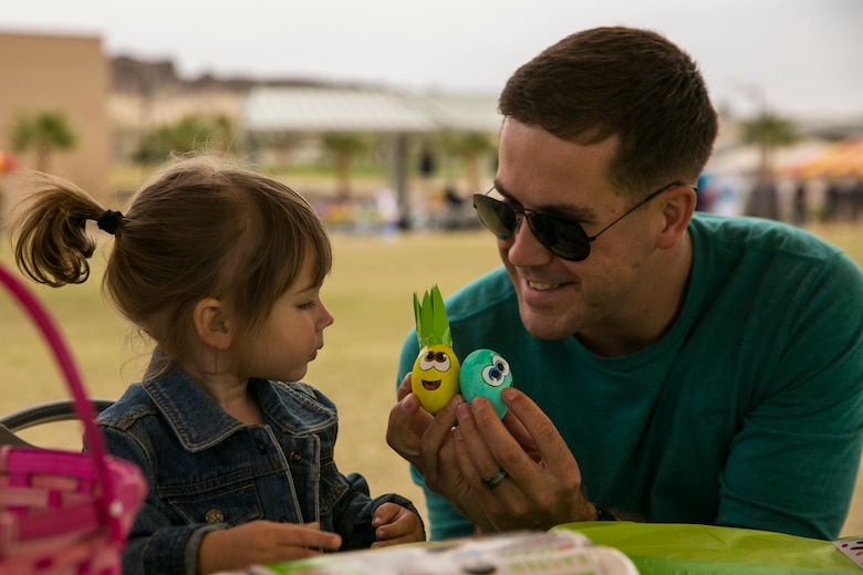 Sgt. Andrew Metler, mortarman, 1st Battalion, 7th Marine Regiment, decorates Easter eggs with his daughter Paisley, 2, during a spring family day at Victory Field aboard the Marine Corps Air Ground Combat Center, Twentynine Palms, Calif., March 24, 2018. The unit family readiness officer hosts events like spring family day to enhance camaraderie, bring spouses together to form positive relationships and create activities for the children. (U.S. Marine Corps photo by Lance Cpl. Margaret Gale)