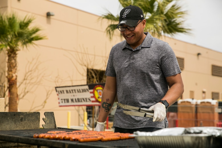 Staff Sgt. Oscar Soto, battalion mess chief, 1st Battalion, 7th Marine Regiment, prepares hot dogs during a spring family day at Victory Field aboard the Marine Corps Air Ground Combat Center, Twentynine Palms, Calif., March 24, 2018. The unit family readiness officer hosts events like spring family day to enhance camaraderie, bring spouses together to form positive relationships and create activities for the children. (U.S. Marine Corps photo by Lance Cpl. Margaret Gale)