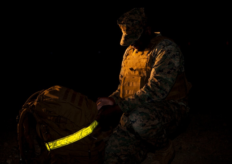 Gunnery Sgt. Jamal A. Russell, operations chief, Alpha Company, Headquarters Battalion, prepares his pack for a 6 mile company hike aboard the Marine Corps Air Ground Combat Center, Twentynine Palms, Calif., March 23, 2018. The Marines regularly conduct company level physical training events in order to maintain physical readiness for upcoming field operations. (U.S. Marine Corps photo by Lance Cpl. Jennessa Davey)