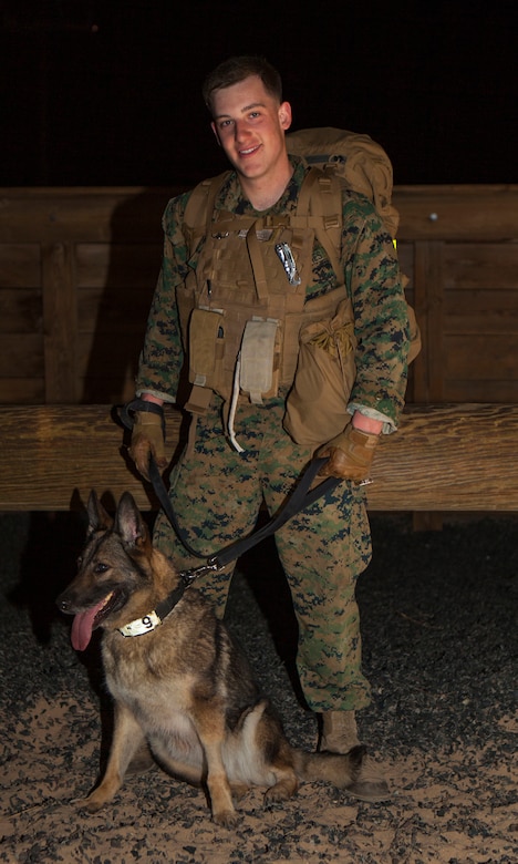 Lance Cpl. Ryan Desselier, military working dog handler, Provost Marshal’s Office, stands with his K-9 Baby at the conclusion of a  6 mile company hike aboard the Marine Corps Air Ground Combat Center, Twentynine Palms, Calif., March 23, 2018. The Marines regularly conduct company level physical training events in order to maintain physical readiness for upcoming field operations. (U.S. Marine Corps photo by Lance Cpl. Jennessa Davey)
