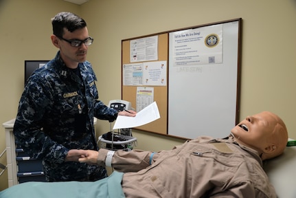 U.S. Navy Lt. Jonathan Carmack, head of Naval Health Clinic Charleston’s Staff, Education and Training Department, inspects a mock patient and its surroundings for potential hazards in NHCC’s “Room of Errors,” Mar. 16, 2018. The room was designed with purposely planted examples of hazards which could cause harm to patients or put their privacy at risk as part of Patient Safety Awareness Week, a national campaign which ran March 11-17.