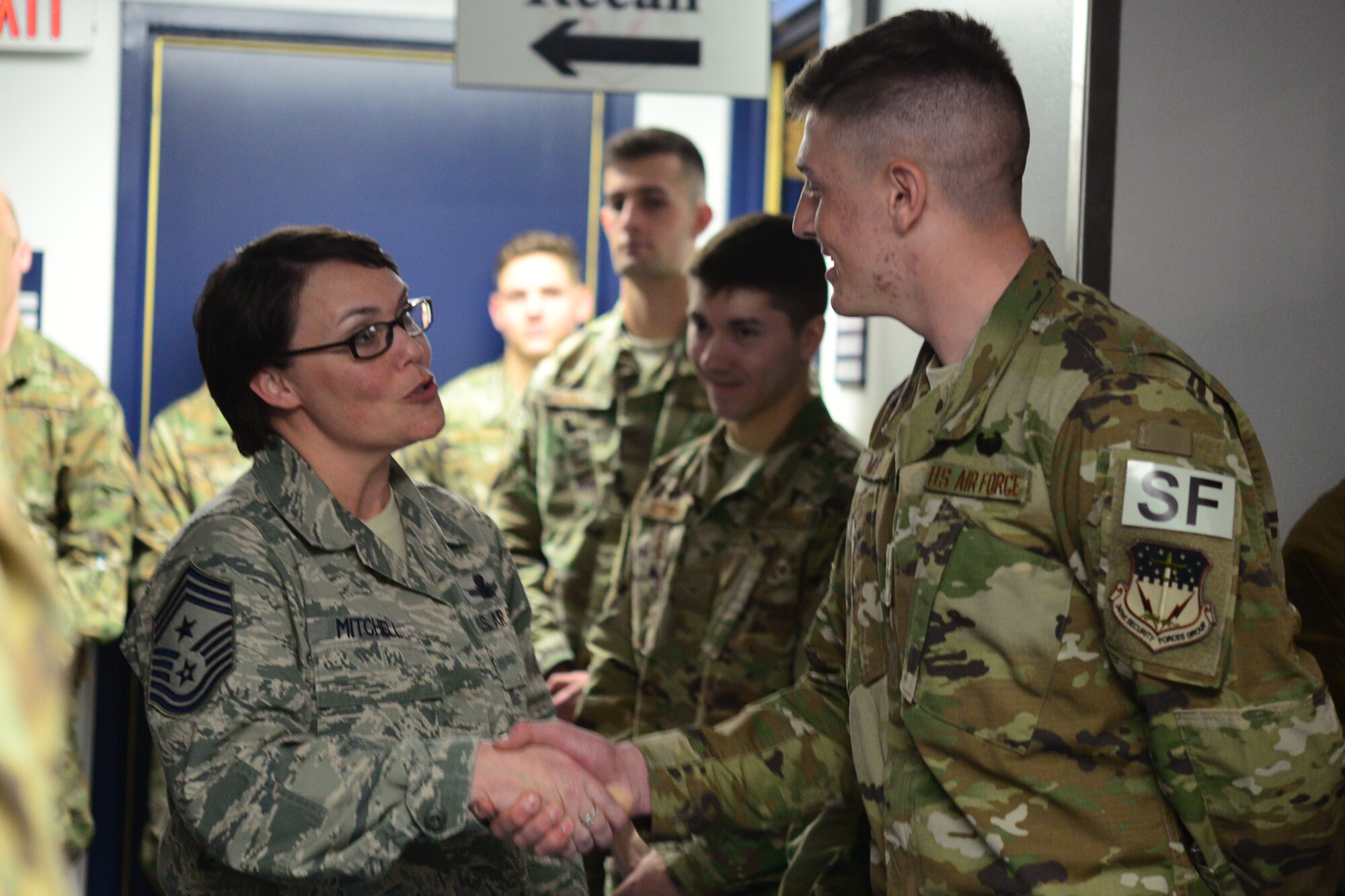 Chief Master Sgt. Amber Mitchell, 341st Missile Wing command chief, left, presents a coin to Airman Gideon Magrini, 841st Missile Security Forces Squadron missile security operator, Mar. 23, 2018, at Malmstrom Air Force Base, Mont.