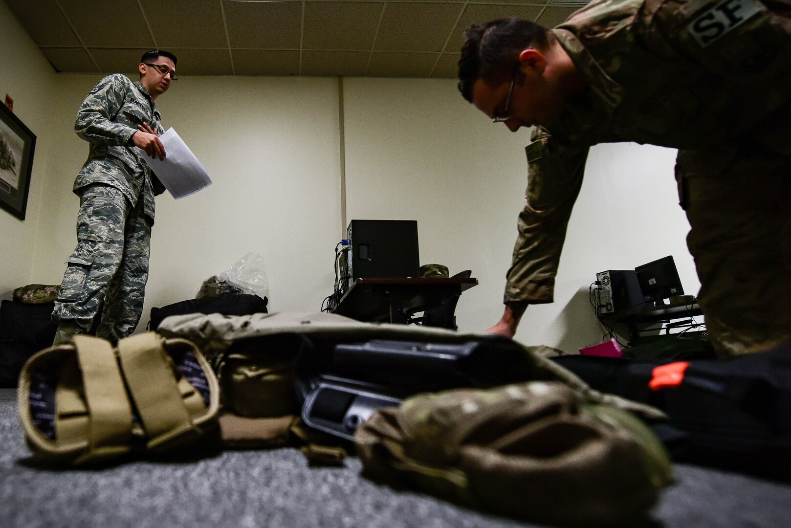 U.S. Air Force Staff Sgt. Justin Martinez, 20th Security Forces Squadron (SFS) unit deployment manager, left, inspects Senior Airman Michael Craig, 20th SFS installation patrolman, as he prepares a deployment bag at Shaw Air Force Base, S.C., March 29, 2018.