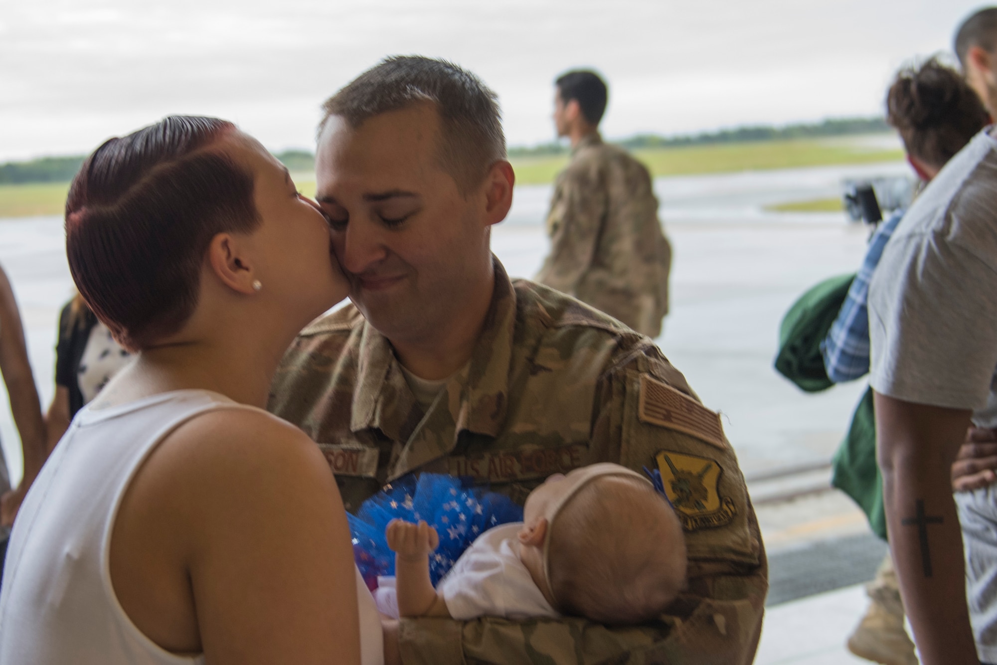 Airman 1st Class Aaron Thompson, 822nd Base Defense Squadron fire team member, receives a kiss from his wife, Jess, and holds his daughter, Luna, during a redeployment ceremony March 30, 2018, at Moody Air Force Base, Ga. The 822nd BDS returned after spending several months deployed and earning numerous command, wing and individual awards. (U.S. Air Force photo by Staff Sgt. Eric Summers Jr.)