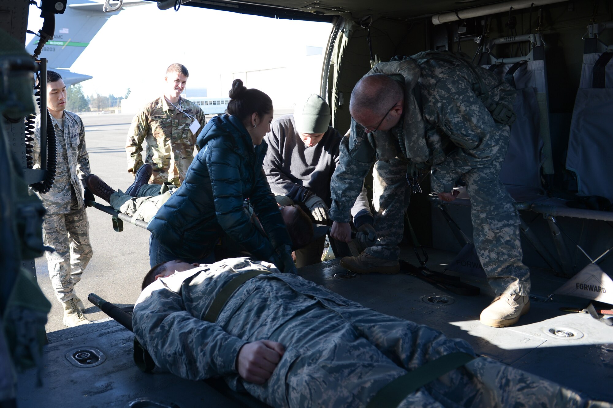Army Sgt. Michael Cummings, Washington National Guard, Detachment 2, 168 General Support Aviation Battalion crew chief, assists members of the Association of Military Osteopathic Physicians and Surgeons load simulated patients into a UH-60 Black Hawk helicopter, March 10, 2018, at Joint Base Lewis-McChord, Wash. Crew chiefs are trained to assist medics during patient transport. (U.S. Air Force photo by Airman 1st Class Sara Hoerichs)