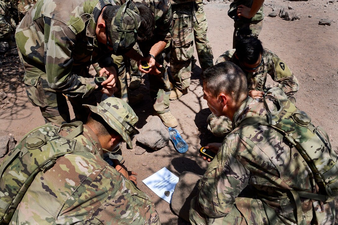U.S. and French soldiers prepare to start desert land navigation.