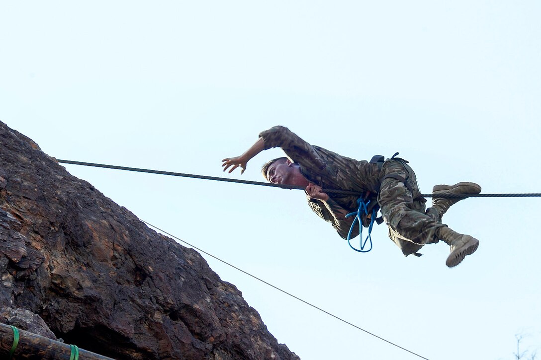 A soldier pulls himself along a single rope bridge.