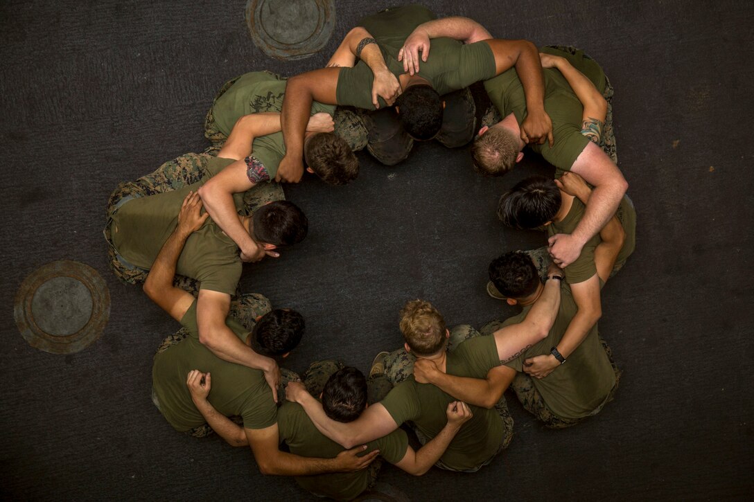 As seen from above, a group of Marines stand in a circle.